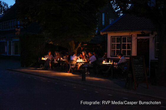 Mensen zitten met noodverlichting op terras na stroomstoring in Blaricum