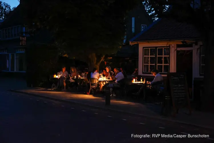 Mensen zitten met noodverlichting op terras na stroomstoring in Blaricum
